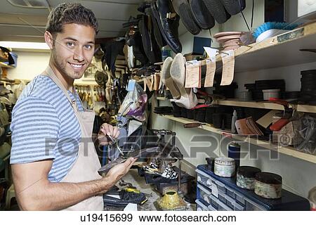 Stock Photo - Portrait of young shoemaker spreading glue on sole of shoe. Fotosearch