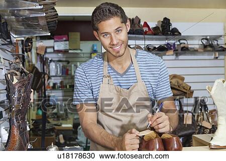 Stock Image - Portrait of young shoemaker writing in workshop. Fotosearch