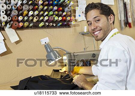 Stock Image - Portrait of young tailor sewing cloth in shop. Fotosearch
