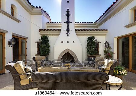 Stock Image - Seating furniture with fireplace in courtyard of luxury mansion. Fotosearch