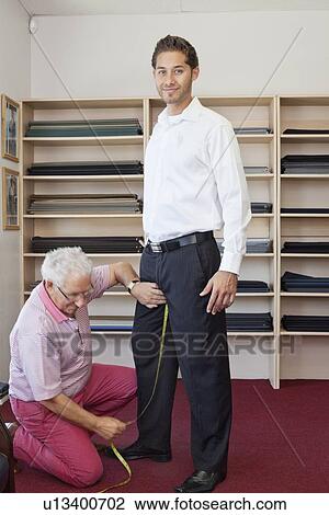 Stock Image - Senior tailor getting customers measurement. Fotosearch