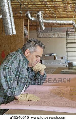 Stock Photography - Side view of mature man looking at blueprint. Fotosearch