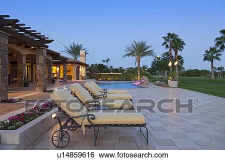 Sun loungers in patio at poolside outside luxurious manor house View Large Photo Image Stock Photograph - Sun loungers in patio at poolside outside luxurious manor house. Fotosearch