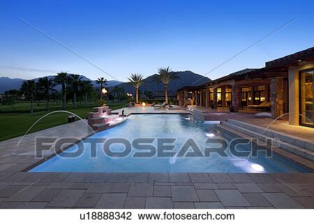 Stock Image - Swimming pool with fountain outside luxurious manor house. Fotosearch