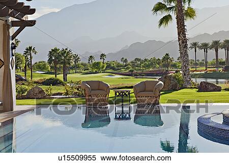 Stock Photography - View of idyllic landscape with mansion swimming pool in foreground. Fotosearch