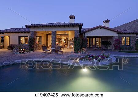 Stock Photography - View of luxury villa with swimming pool in evening. Fotosearch