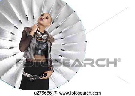 Stock Photo - Young African American woman thinking while standing in front of reflector umbrella in studio. Fotosearch