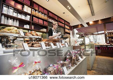 Young female attendant working in bakery store with pastries on display View Large Photo Image Stock Photograph - Young female attendant working in bakery store with pastries on display. Fotosearch