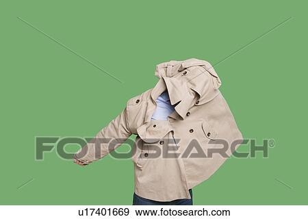 Young man struggling to wear jacket over colored background View Large Photo Image Stock Photo - Young man struggling to wear jacket over colored background. Fotosearch