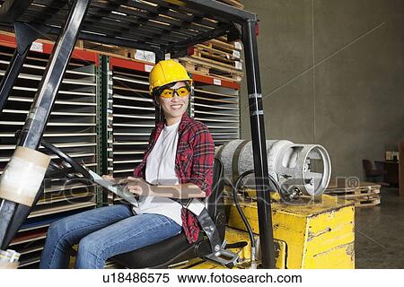 Asian female industrial worker with clipboard looking away while sitting in forklift truck View Large Photo Image Stock Photography - Asian female industrial worker with clipboard looking away while sitting in forklift truck. Fotosearch