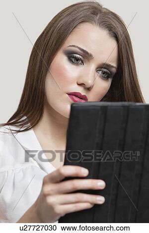 Beautiful young woman using tablet PC over gray background View Large Photo Image Stock Image - Beautiful young woman using tablet PC over gray background. Fotosearch
