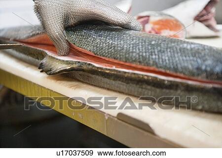 Stock Photo - Close-up of man's hand with slicing salmon fish. Fotosearch