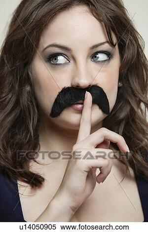 Close-up of young woman with finger on lips wearing fake mustache View Large Photo Image Stock Photography - Close-up of young woman with finger on lips wearing fake mustache. Fotosearch