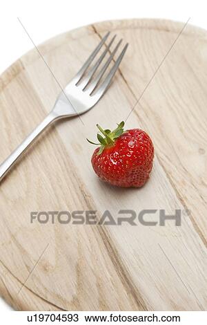 Stock Image - Cropped shot of wooden plate with strawberry and fork on it. Fotosearch