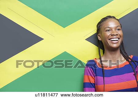 Stock Photo - Excited young woman with braided hair against Jamaican flag. Fotosearch