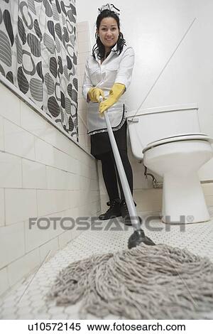 Stock Photography - Full length portrait of maidservant cleaning bathroom floor. Fotosearch