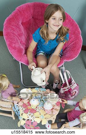 Stock Photography - Girl pretending to have tea party with her dolls. Fotosearch