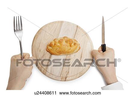 Hands holding knife and fork with Cornish pastry on wooden plate over white background View Large Photo Image Stock Image - Hands holding knife and fork with Cornish pastry on wooden plate over white background. Fotosearch