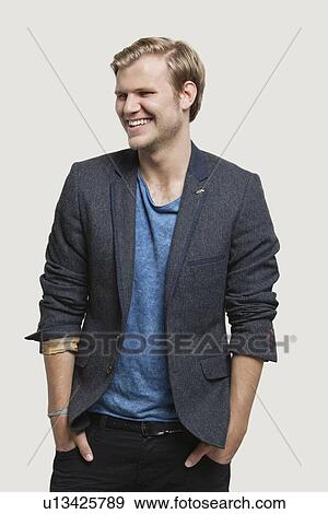 Happy businessman in smart casuals looking away against gray background View Large Photo Image Stock Photo - Happy businessman in smart casuals looking away against gray background. Fotosearch