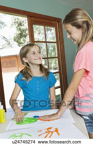 Happy young sisters making hand prints on paper View Large Photo Image Picture - Happy young sisters making hand prints on paper. Fotosearch
