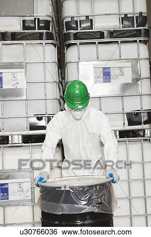 Industrial worker in hazmat suit holding plastic covered chemical drum View Large Photo Image Stock Photograph - Industrial worker in hazmat suit holding plastic covered chemical drum. Fotosearch