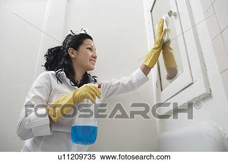 Low angle view of young housemaid cleaning mirror View Large Photo Image Stock Photography - Low angle view of young housemaid cleaning mirror. Fotosearch