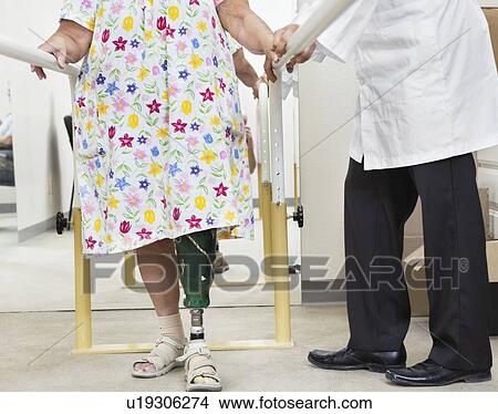 Picture - Low section of female patient being assisted by a technician. Fotosearch