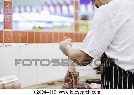 Stock Photo - Man working in butcher shop. Fotosearch