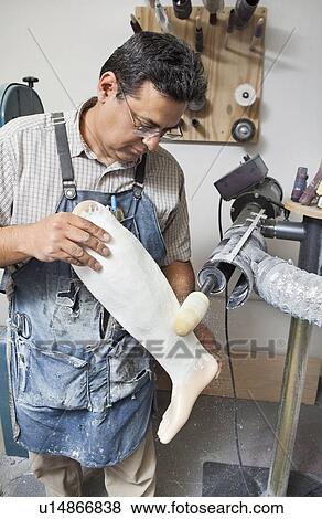 Stock Photo - Mature male worker buffing prosthetic limb. Fotosearch