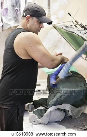 Stock Photo - Mature man ironing shirt in laundry. Fotosearch