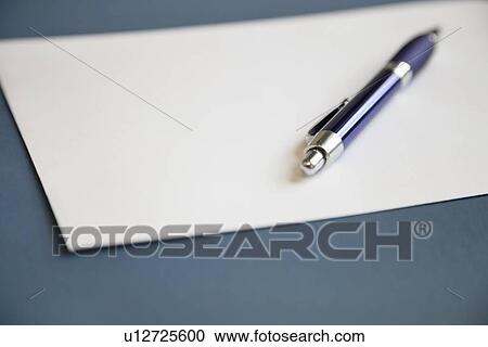 Stock Image - Metallic pen on a blank white paper over dark blue background. Fotosearch