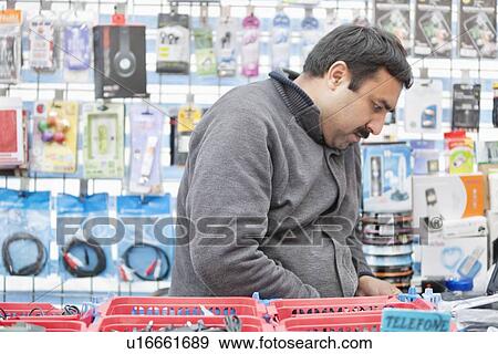 Stock Photo - Mid adult male sales clerk working in electronics store. Fotosearch