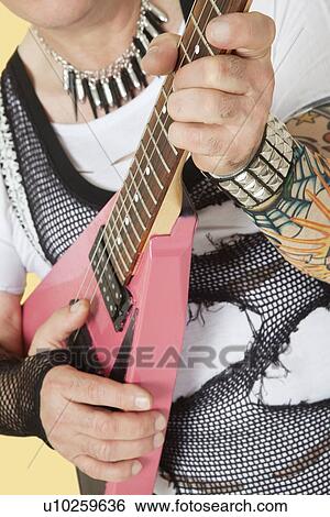 Stock Photograph - Midsection of senior male punk musician playing guitar. Fotosearch