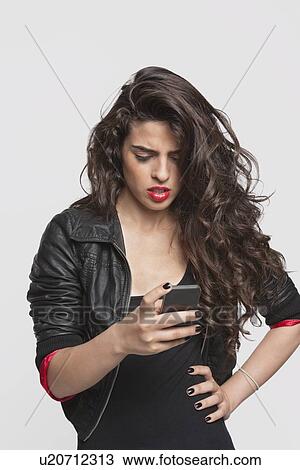 Pensive young woman using cell phone over gray background View Large Photo Image Stock Image - Pensive young woman using cell phone over gray background. Fotosearch