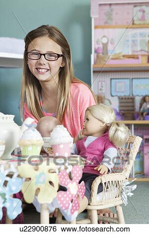 Portrait of a happy girl playing with doll View Large Photo Image Stock Photograph - Portrait of a happy girl playing with doll. Fotosearch