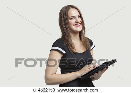Portrait of a happy woman using tablet PC over gray background View Large Photo Image Stock Image - Portrait of a happy woman using tablet PC over gray background. Fotosearch