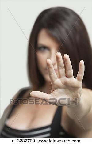 Portrait of a young woman gesturing stop sign over gray background View Large Photo Image Stock Photo - Portrait of a young woman gesturing stop sign over gray background. Fotosearch