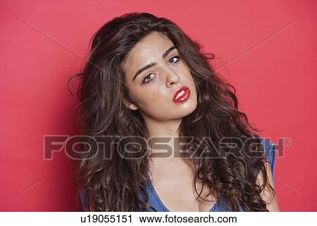 Stock Image - Portrait of an attractive young woman over red background. Fotosearch