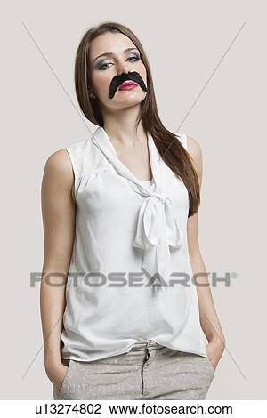 Portrait of beautiful young woman with fake mustache against gray background View Large Photo Image Stock Image - Portrait of beautiful young woman with fake mustache against gray background. Fotosearch