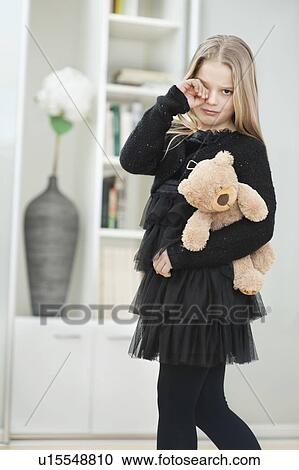Stock Image - Portrait of crying young girl with teddy bear. Fotosearch