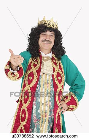 Stock Image - Portrait of happy king with hand gesture over gray background. Fotosearch