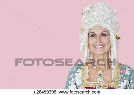 Stock Photograph - Portrait of happy senior queen against pink background. Fotosearch