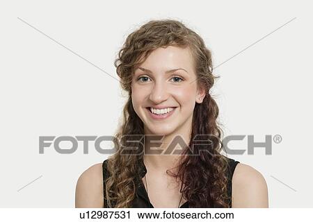 Stock Image - Portrait of happy young woman with curly hair against gray back ground. Fotosearch