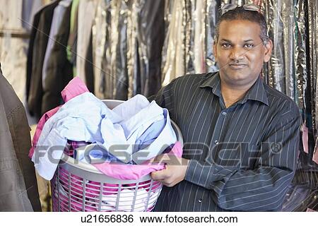 Stock Photograph - Portrait of man holding laundry basket. Fotosearch
