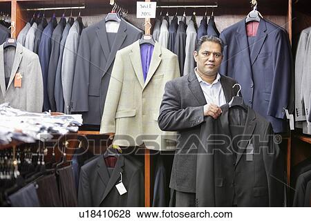 Portrait of man shopping for formal coat in menswear store View Large Photo Image Stock Photo - Portrait of man shopping for formal coat in menswear store. Fotosearch