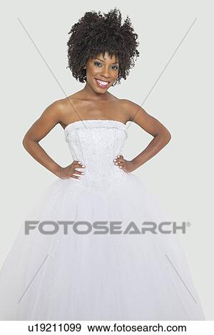 Stock Photo - Portrait of pretty African American bride standing hands on hips against gray background. Fotosearch