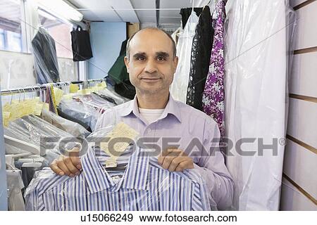 Portrait of senior man holding dry cleaned shirt View Large Photo Image Stock Photo - Portrait of senior man holding dry cleaned shirt. Fotosearch