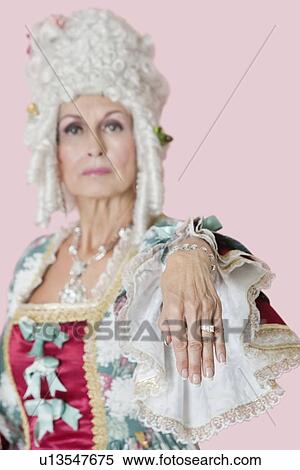 Portrait of senior queen stretching out her hand over pink background View Large Photo Image Stock Photography - Portrait of senior queen stretching out her hand over pink background. Fotosearch