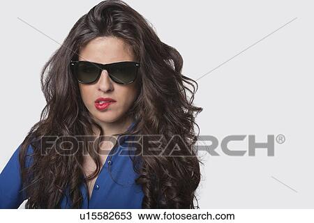 Portrait of sensuous young woman wearing sunglasses while biting lip over gray background View Large Photo Image Stock Image - Portrait of sensuous young woman wearing sunglasses while biting lip over gray background. Fotosearch