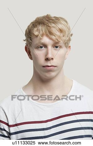 Stock Photography - Portrait of serious young man over gray background. Fotosearch